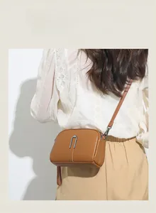Detail view of a tan lychee pattern leather handbag with silver U-shaped metal accent
