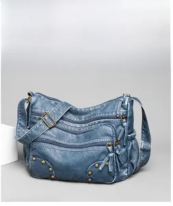 Detail view of washed leather texture and bronze rivets on blue crossbody bag