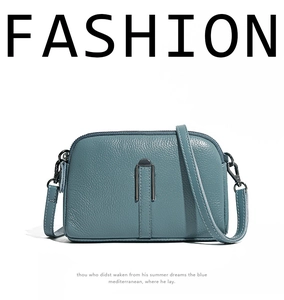 Detail of teal pebble leather crossbody bag with silver U-shaped metal buckle accent