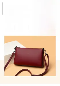 Macro detail of wine red litchi texture leather shoulder bag with metal logo