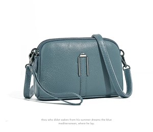 Detail view of the premium pebbled leather texture and U-shaped metal hardware on the blue bag
