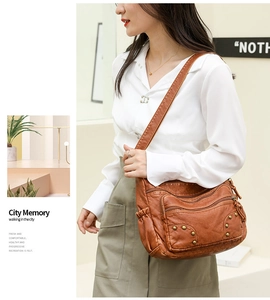 Detail of a brown PU leather crossbody bag with multi-zipper pockets and brass rivets