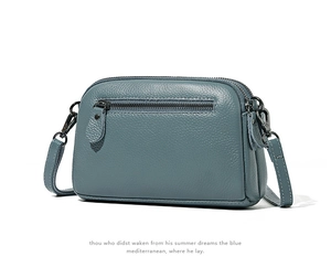 Detailed view of grey-blue pebble leather handbag with multiple zippers and silver hardware