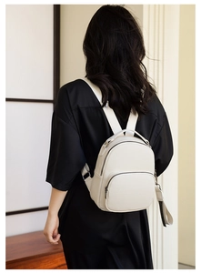 Close-up of soft white PU leather backpack with lychee texture and front zipper pocket