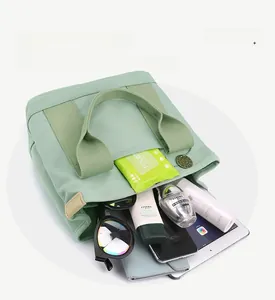 Detail view of large mint green canvas tote bag showing spacious multi-compartment storage