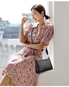 Detail of black lychee grain leather crossbody bag with silver hardware and logo