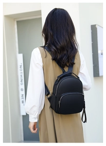 Detail view of mini black lychee textured leather backpack with adjustable straps on model