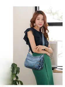 Detail view of denim texture shoulder bag with studs and multiple zipper pockets