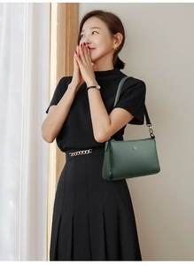 Detail of dark green leather shoulder bag with lychee texture and geometric logo