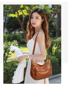 Outdoor shot of a vintage brown PU leather crossbody bag with rivet details and pockets