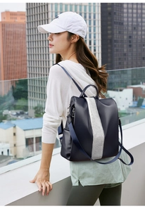 Detailed side view of navy blue PU leather backpack with silver strap and lychee texture