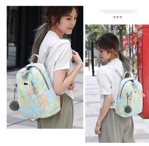Photo lifestyle d'un sac à dos en oxford avec imprimé floral et détail de pompon gris