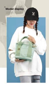 Close-up of light green canvas handbag featuring multiple pockets and gold metal charm
