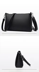 Detail view of black lychee grain leather crossbody bag with silver square metal logo buckle