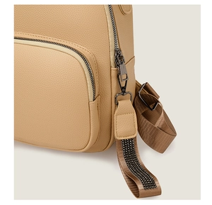 Detail of beige lychee textured PU leather backpack with dark metal zipper and rhinestones