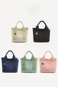 Detail display of five canvas tote bags in khaki, black, blue, green, and pink colors
