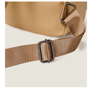 Close-up of camel lychee leather texture and brown nylon strap with gun-metal hardware