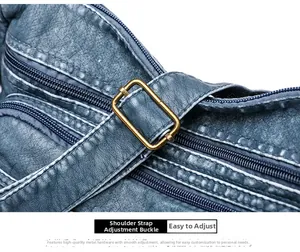 Detail of adjustable bronze buckle and multiple zippers on a blue-grey faux leather bag