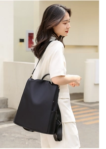 Detail of multi-way oxford backpack worn on shoulder against a minimalist white wall