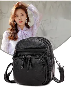 Detail of black soft leather crossbody bag showing multi-zipper layers and texture
