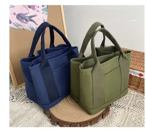 Detail of multi-pocket canvas tote bags in navy and olive with triple compartment storage