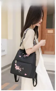 Detail of pink floral embroidery and butterfly patterns on a black nylon backpack