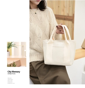 Detailed view of cream canvas tote bag with functional pockets and reinforced handles