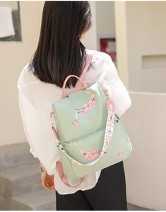 Detail of mint green nylon backpack with pink cherry blossom embroidery and floral strap