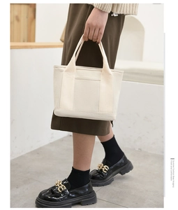 Detail of minimalist cream canvas handbag with reinforced handles and clean stitching