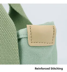 Detailed close-up showing reinforced stitching and premium leather trim on canvas handbag