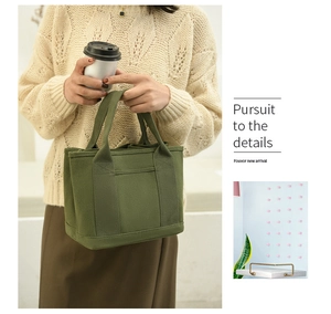 Detail showing the army green canvas handbag with a front pocket and durable handles