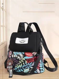 Detail view of stylish waterproof backpack with tropical leaf print and cute bear charm