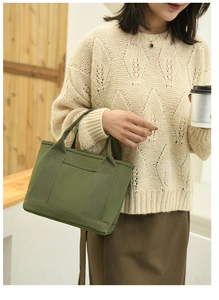 Olive green canvas tote bag with front pocket shown in an indoor lifestyle setting