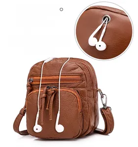Detail of brown PU leather bag featuring a functional external earphone hole and zippers