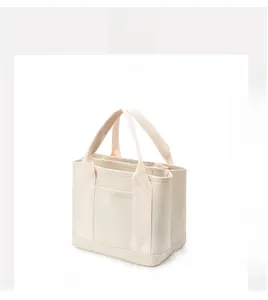 Detailed side view of off-white canvas handbag showing multi-compartment storage structure