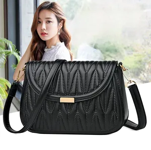 Close-up of black quilted PU leather shoulder bag with gold hardware and V-pattern stitching