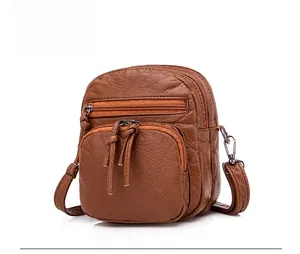 Detail view of brown pebbled PU leather shoulder bag with multiple zippered compartments