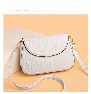 Detail of white PU leather crossbody bag with elegant wave quilted texture and gold clasp