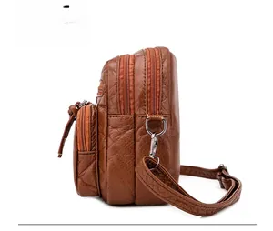 Detailed side view of brown litchi leather crossbody bag with triple zipper design