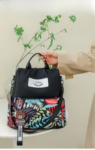 Detail of waterproof nylon backpack with tropical leaf print and brown bear charm