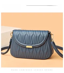 Close-up of blue quilted PU leather shoulder bag featuring wavy stitching and golden hardware