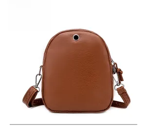 Macro detail of brown leather crossbody bag back showing headphone hole and metal hardware