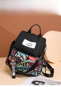 Detail of printed backpack with tropical leaf pattern, side pocket and cartoon bear charm