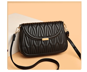 Detail of black quilted shoulder bag with wave texture and gold metallic hardware clasp