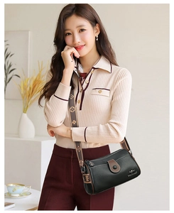 Détail d'un sac bandoulière en cuir noir avec une large bandoulière imprimée décorative