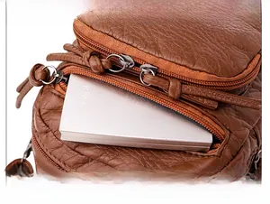 Macro detail of brown litchi texture crossbody bag showing front zipper functional pocket