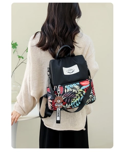 Detail of floral print backpack with a cute teddy bear charm and durable fabric texture