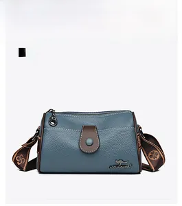 Vue détaillée du sac à bandoulière en cuir bleu avec finitions brunes et logo en métal