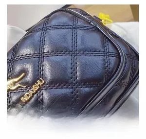 Close-up of black quilted leather stitching with golden kangaroo logo detail