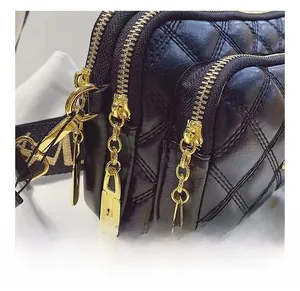 Detail view of the triple layered zipper compartments on black quilted crossbody bag